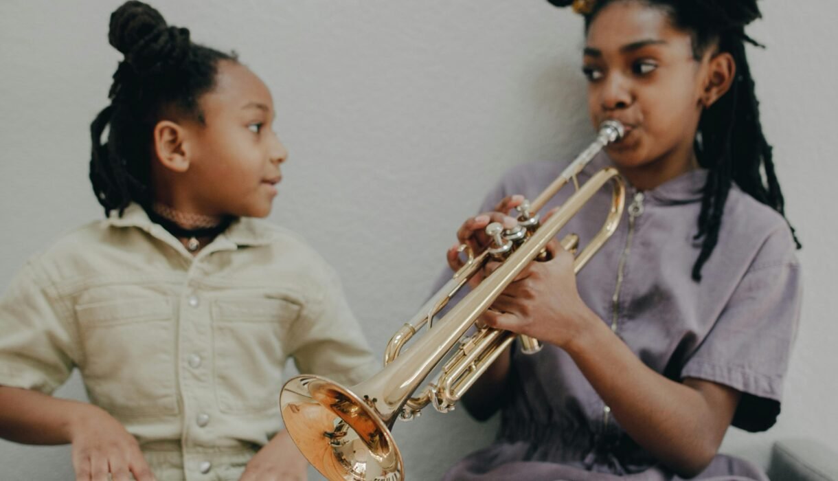Two girls enjoying music at home with a keyboard and trumpet.