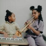 Two girls enjoying music at home with a keyboard and trumpet.