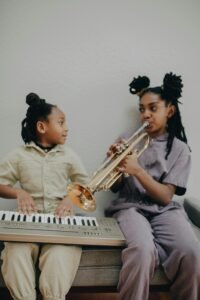 Two girls enjoying music at home with a keyboard and trumpet.