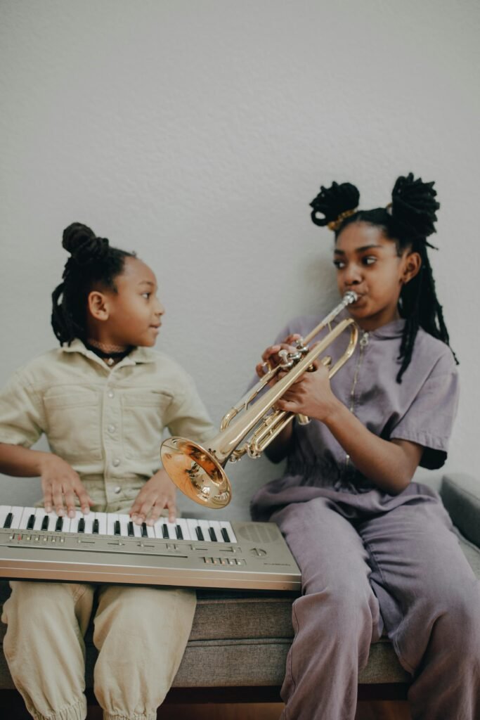 Two girls enjoying music at home with a keyboard and trumpet.
